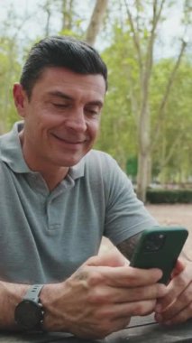 Parktaki bankta oturan adam ailesini selamlıyor.