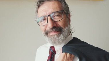 Yakından, yetişkin iş adamı kameraya bakıyor ve gri arka planda gülümsüyor.