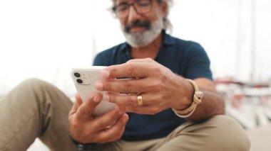 Cep telefonu tutan yaşlı bir adamın elleri yakın plan, arka plan bulanık
