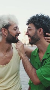 Eşcinsel çift sokakta otururken birbirlerine sarılıp öpüşürler.