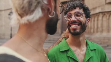 Eski şehrin caddesinde dikilmiş gülen eşcinsel çiftin yakın çekimi