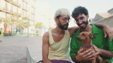 Homoseksüel çift dışarıda otururken köpeğini okşuyor.
