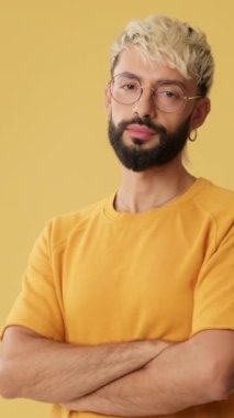 Başparmak hareketi gösteren genç adam, stüdyoda sarı arka planda izole kameraya bakıyor.