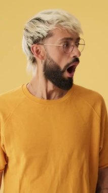 Adam reklam alanına bakıyor, şaşırıyor, vay, stüdyoda sarı arka planda izole edilmiş.