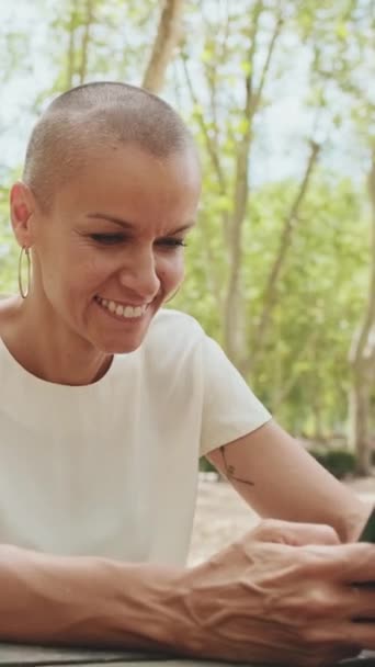 Vacker Lycklig Kvinna Rullar Sin Telefon När Hon Sitter Parkbänk — Stockvideo