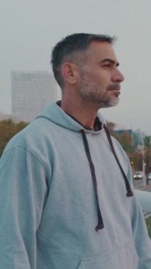 Spor giyimli orta yaşlı bir adam köprü boyunca yürüyor.