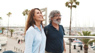 Mutlu orta yaşlı çift yaz günü şehirde yürüyor. Emekli yaşlı çift birlikte dışarıda eğleniyor.