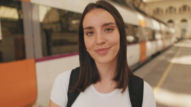 Tren istasyonunda kameraya gülümseyen bir kadının yakın çekimi.