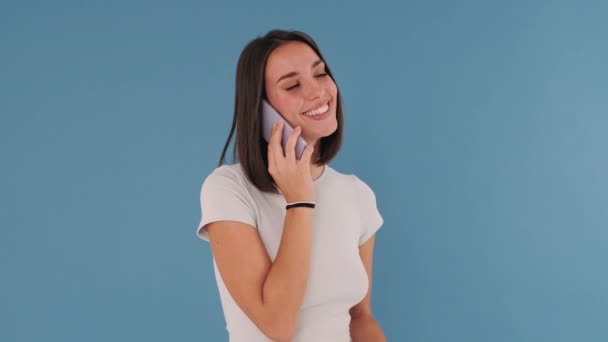 Jonge Vrouw Praten Mobiele Telefoon Geïsoleerd Blauwe Achtergrond Studio — Stockvideo