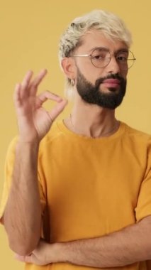 Genç adam iyi bir hareket sergiliyor. Stüdyoda sarı arka planda izole edilmiş kameraya bakıyor.