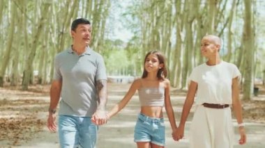 Şehir parkında el ele tutuşan mutlu bir aile.