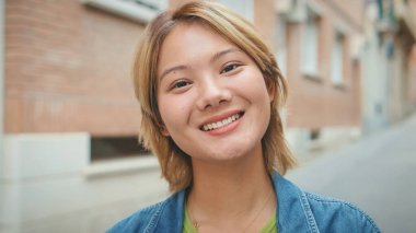 Kameraya bakan gülümseyen genç bir kadının yakın çekimi.