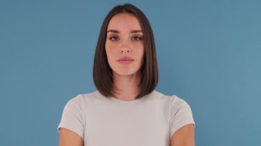 Kapatın, kameraya bakan kadın stüdyoda mavi arka planda izole edilmiş.