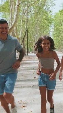 Şehir parkında koşan mutlu bir aile.