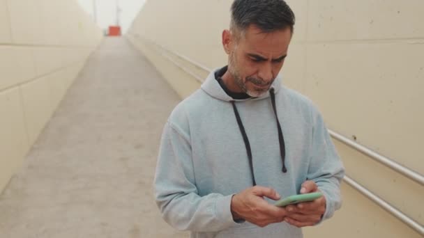 Medelålders Man Sportkläder Använder Mobiltelefon Efter Träningen — Stockvideo