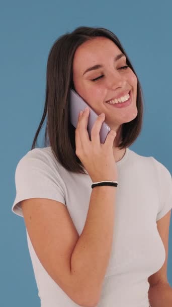 在演播室里用蓝色背景的手机交谈的年轻女人 — 图库视频影像