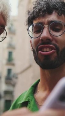 Yakın plan, eski şehrin caddesinde cep telefonuna bakan homoseksüel çift.