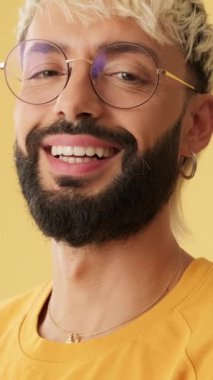 Resim, gülen adam stüdyoda sarı arka planda izole edilmiş kameraya bakıyor.