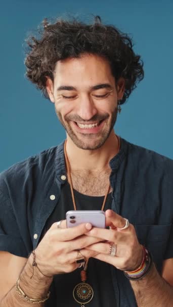 Gülümseyen Adam Cep Telefonu Kullanıyor Stüdyoda Mavi Arka Planda Izole — Stok video