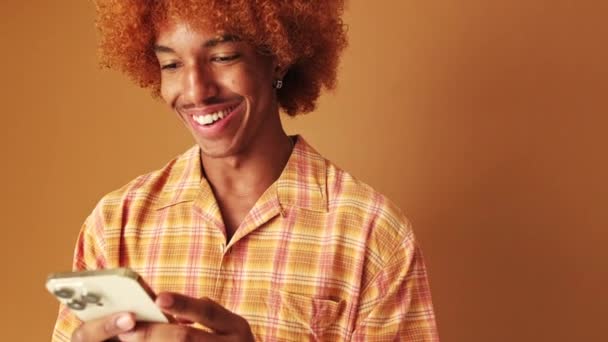 Cep Telefonu Kullanan Gülümseyen Bir Adam Stüdyoda Kahverengi Arka Planda — Stok video