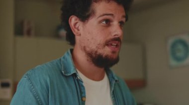 Oturma odasında konuşan ve el kol hareketi yapan adamın yakın çekimi.