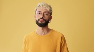Adam parmağını sallıyor, olumsuz cevap veriyor, sarı arkaplanda izole kameraya bakıyor.