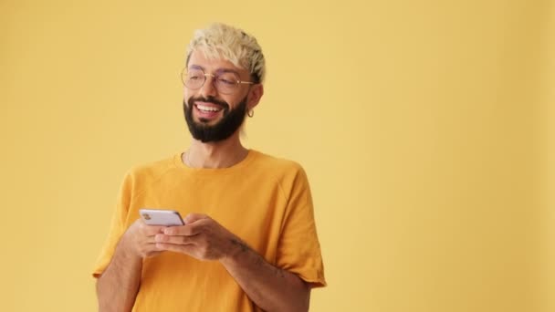 Uśmiechnięty Mężczyzna Piszący Smsy Telefonie Komórkowym Odizolowany Żółtym Tle Studio — Wideo stockowe