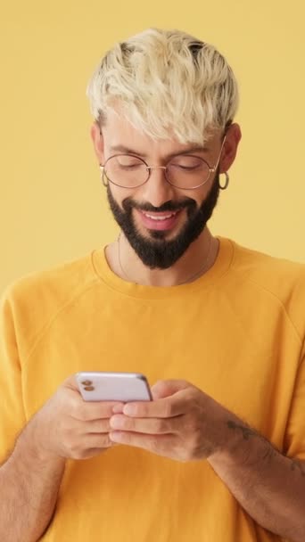 Uśmiechnięty Mężczyzna Telefonem Ręku Makietą Odizolowany Żółtym Tle Studio — Wideo stockowe