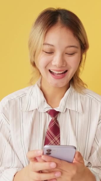 Smějící Mladá Žena Baví Při Pohledu Mobilní Telefon Izolované Žlutém — Stock video