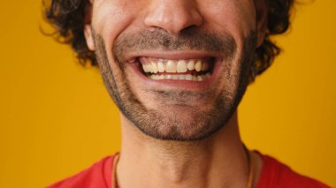 Stüdyoda, sarı arka planda bir adamın gülümsemesinin detaylı görüntüsü.