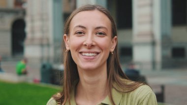 Eski şehrin arka planında kameraya bakan güzel, gülen bir kadının yakın çekimi.