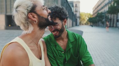 Homoseksüel çiftler sokakta otururken birbirleriyle konuşmaktan zevk alırlar.
