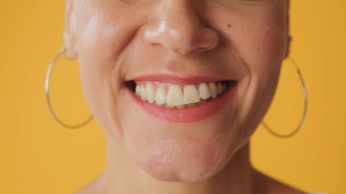 Sarı arka planda izole edilmiş bir kadının gülüşünün detaylı görüntüsü.