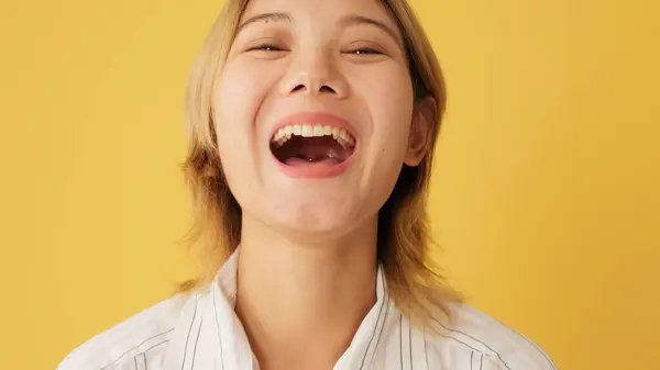 Close-up of laughing woman looking at camera isolated on yellow background in studio
