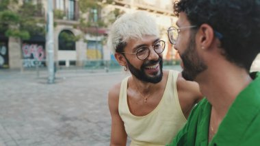 İki erkek turist sokakta otururken sohbet ediyorlar.