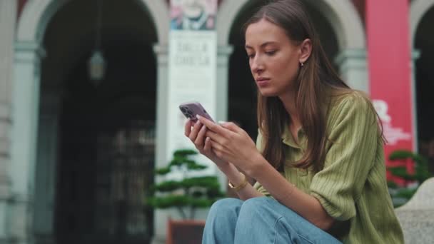Giovane Donna Utilizza Telefono Mentre Seduto Sulla Piazza Della Città — Video Stock