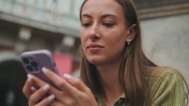 Kahverengi saçlı, zeytin yeşili kazak giyen sosyal medyada cep telefonu uygulaması mesajları kullanan bir kadın.