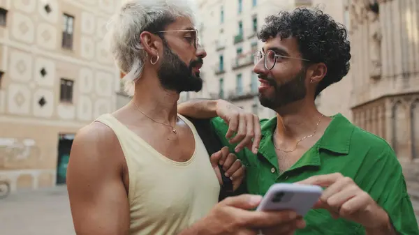 Homosexual couple uses map application on mobile phone while standing on street of old city