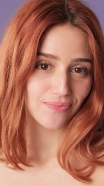 Yakın plan, gülümseyen flört eden kız mor arka plandaki kameraya bakıyor.