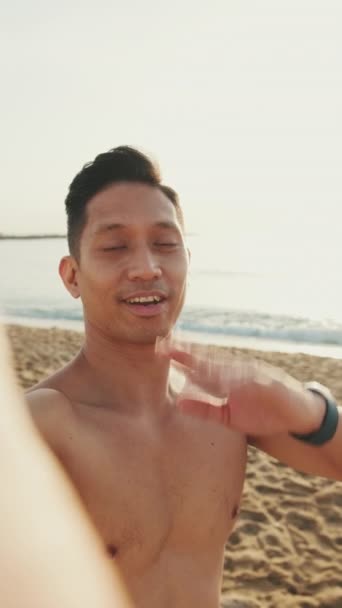 Κοντινό Πλάνο Νεαρός Αθλητικός Άντρας Στέκεται Στην Παραλία Βγάζοντας Μια — Αρχείο Βίντεο