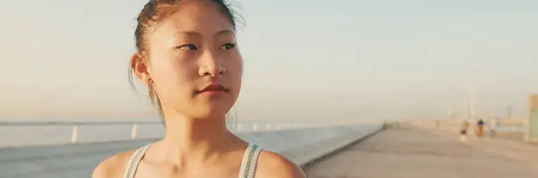 Asian girl in sports top walking outside at morning time, Panorama