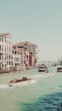Dikey video, Venedik Kanalı, turistlerle dolu tekneler ve gondollar güneşli bir günde kanal boyunca yüzerler.