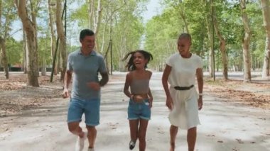 Şehir parkında koşan mutlu bir aile.