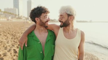 Yakın plan mutlu eşcinsel çift kumsalda yürüyor.