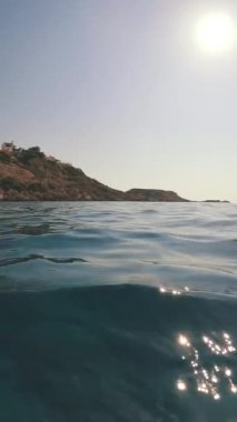 Kıyı kayaları olan su yüzeyi, alçak açılı çekim, arka plan ışığı, deniz manzarası