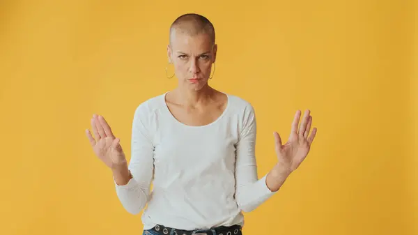 stock image Young hairless woman listens carefully and strongly disagrees, looking at camera isolated on yellow background in studio