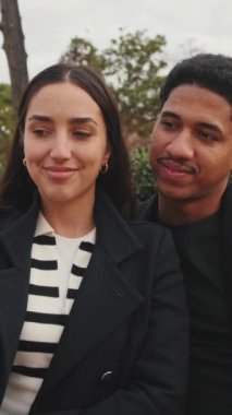 Çok ırklı bir çift parkta akıllı telefonla selfie çekiyor..