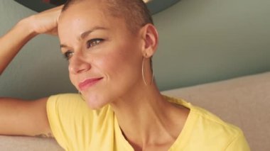 Oturma odasındaki kanepede dinlenen düşünceli kel kadının yakın plan portresi.