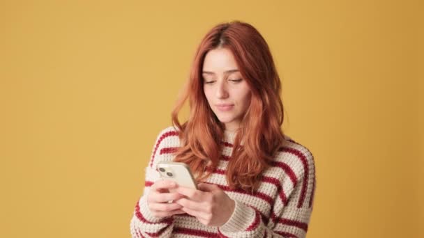 Meisje Met Mobiele Telefoon Handen Viert Overwinning Gele Achtergrond — Stockvideo