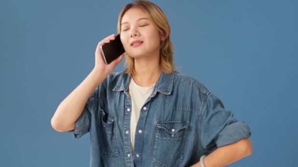 Upprörd Ung Kvinna Talar Mobiltelefon Isolerad Blå Bakgrund — Stockvideo